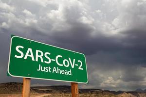 SARS-CoV-2 coronavirus grön väg tecken mot olycksbådande stormig molnig himmel foto