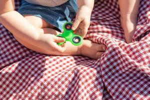 bebis pojke Sammanträde på picknick filt spelar med fidget spinnare foto