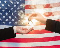 lämnandet över hus nycklar i främre av amerikan flagga foto
