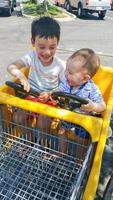 förtjusande kinesisk och caucasian bebis pojke och bror har roligt i matvaror vagn foto