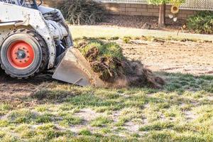 små bulldozer avlägsnande gräs från gård framställning för slå samman installation foto