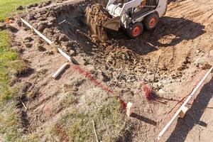 små bulldozer grävning i gård för slå samman installation foto