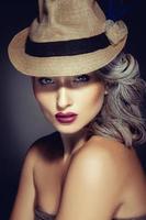 kvinna med skön smink och eleganta hatt ser på kamera foto