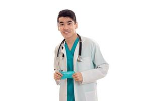 ung stilig läkare i blå enhetlig med stetoskop på hans nacke isolerat på vit bakgrund foto