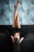 charmig kvinna i svart klänning på en soffa foto