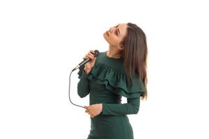 härlig ung flicka i grön klänning sjunger en karaoke foto
