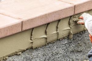 bricka arbetstagare applicering cement med murslev på slå samman konstruktion webbplats foto
