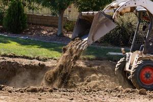 små bulldozer grävning i gård för slå samman installation foto