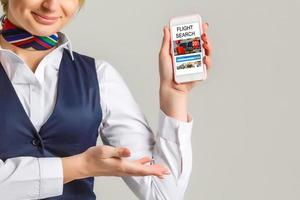 skön ung Flygvärdinnan innehav en smart telefon isolerat på vit bakgrund foto
