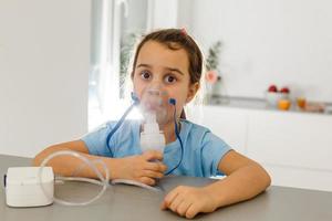 liten flicka i en mask, behandlingar respiratorisk tarmkanalen med en nebulisator på Hem foto