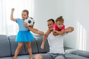 en familj av fläktar tittar på en fotboll match på TV på Hem foto