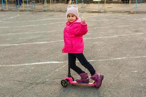 barn ridning skoter. unge på färgrik sparka styrelse. aktiva utomhus- roligt för ungar. sommar sporter för förskola barn. liten flicka i vår parkera. foto