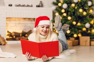 skön ung kvinna ser fotobok i främre av jul träd foto