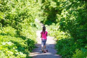 barn ridning skoter. unge på färgrik sparka styrelse. aktiva utomhus- roligt för ungar. sommar sporter för förskola barn. liten flicka i vår parkera foto