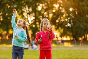 två ung caucasian flickor blåser bubblor foto