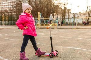 liten skön flicka ridning skoter på stadion foto