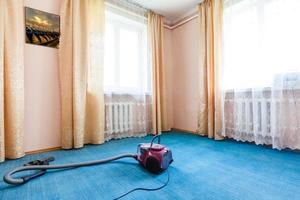 Vakuum rengöringsmedel stående på parkett golv i främre av soffa i levande rum foto