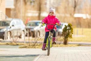 liten flicka med hjälm ridning cykel på solnedgång foto