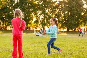 förtjusande liten flickor har roligt spelar utomhus på sommar dag foto