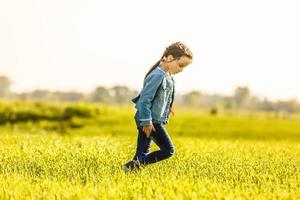 liten flicka ensam på de äng i sommar dag foto