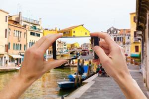 en mobil telefon snäpp en bild av en gondoljär på hans gondol i Venedig foto