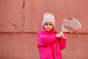liten söt flicka spelar tennis utomhus foto