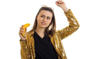 rolig eleganta kvinna i gyllene jacka med banan i händer foto