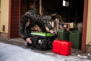 man ha på sig i militär jacka med bensin bärbar mobil säkerhetskopiering står fast vid generator. foto