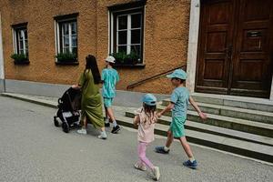 mor med bebis transport och barn gående i hallstatt, Österrike. foto