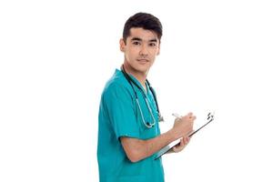 porträtt av skön ung brunett manlig läkare i enhetlig med stetoskop Framställ isolerat på vit bakgrund foto
