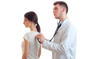 ung kille-läkare i vit labb täcka stetoskop lyssnar tillbaka kvinna foto