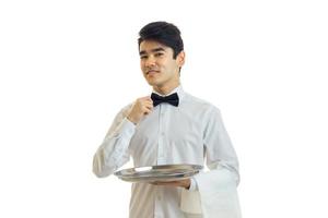 charmig servitör i en vit skjorta innehav en bricka, och justerar hans rosett foto