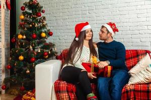 härlig Lycklig par på soffa med jul gåvor foto