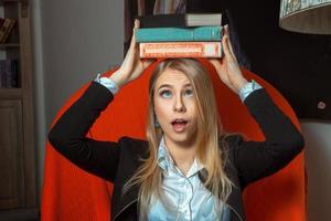 blond flicka med böcker på henne huvud foto