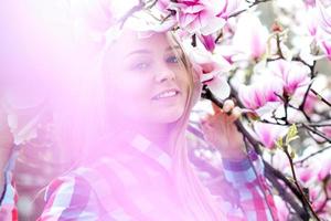 underbar ung blond kvinna leende i rosa blomning blommor foto