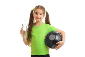 charmig liten flicka i grön enhetlig med fotboll boll foto