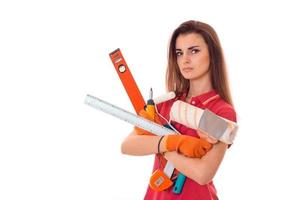ung allvarlig kvinna med mörk hår i uniforl gör renoveringar med verktyg i henne händer isolerat på vit bakgrund foto