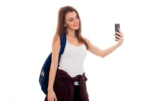 attraktiv ung brunett studenter tonåring i eleganta kläder och ryggsäck på henne axlar Framställ isolerat på vit bakgrund foto