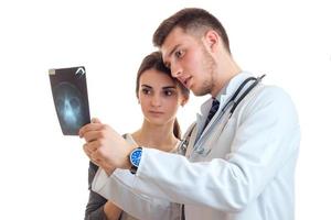 allvarlig ung läkare i en vit labb täcka ser kvinna röntgen foto