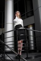 ung chic företag flicka i vit skjorta och svart kjol ler foto