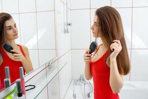 kvinna kammande henne hår i de badrum foto