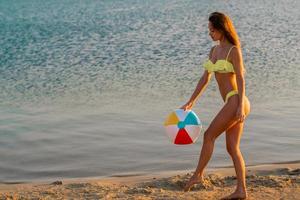 förtjusande smal lady i baddräkt med strand boll i de hav foto