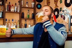 vuxen kille i en bar dricka en utsökt glas av ljus öl foto