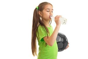 liten flicka i grön skjorta drycker vatten från en flaska foto