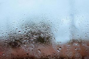 regndroppe faller ner på glas fönster för suddigt begrepp bakgrund foto