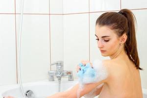skön flicka är tvättades i en varm badkar med skum foto