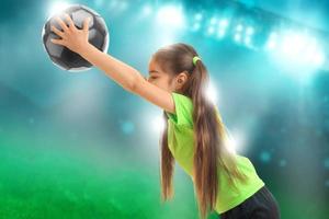 liten flicka i sporter enhetlig spelar fotboll foto