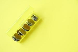stänga upp av mynt i en plast låda på gul bakgrund foto