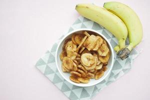 torr banan pommes frites i en skål på svart plattor bakgrund foto