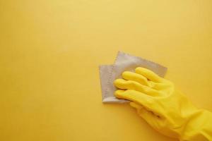hand i gul sudd handskar rengöring gul platt bakgrund foto